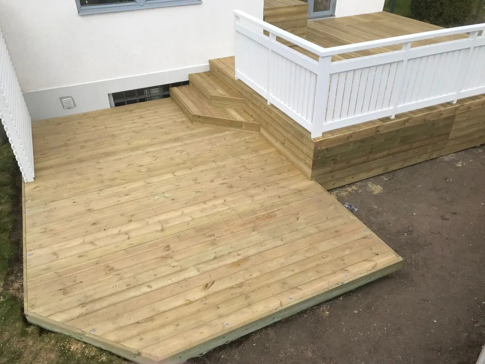 Nybyggt trädäck i två nivåer med vitt räcke, byggt av Wood & Stone